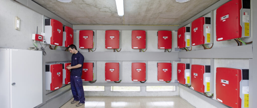 Mitarbeiter prüft rote Energiekästen in einem Raum